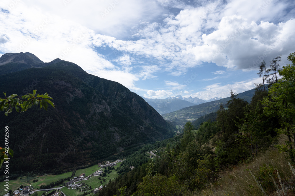 View of the valley from Doues, Valpelline. Mountains, trees, cloudy sky. Villages in the distance. View of the valley from Doues, Valpelline. Mountains, trees, cloudy sky. Villages in the distance.