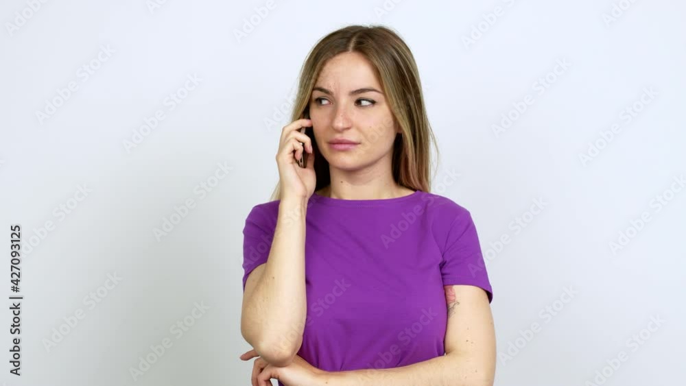 Young woman talking on mobile phone looking side over isolated background Young woman talking on mobile phone looking side over isolated background