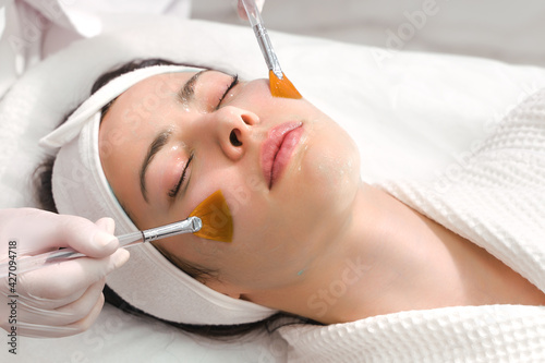 Facial skin care. A mask is applied to a woman's face in a cosmetology clinic. Close up