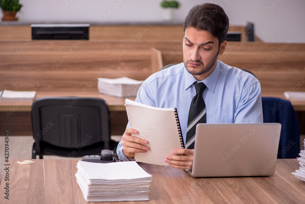 Young male employee and too much work in the office Young male employee and too much work in the office