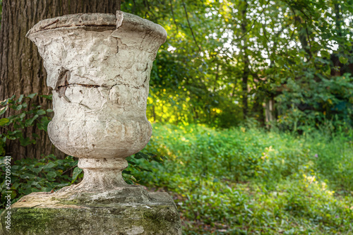 decorative stone vase on a pedestal in an old abandoned park