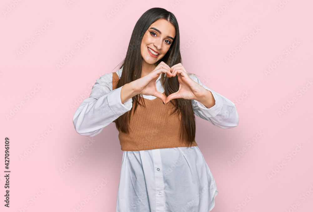 Young beautiful woman wearing casual white shirt smiling in love showing heart symbol and shape with hands. romantic concept. Young beautiful woman wearing casual white shirt smiling in love showing heart symbol and shape with hands. romantic concept.