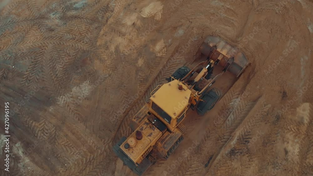 Excavator or bulldozer working on construction site with sand aerial top view. Excavator or bulldozer working on construction site with sand aerial top view.