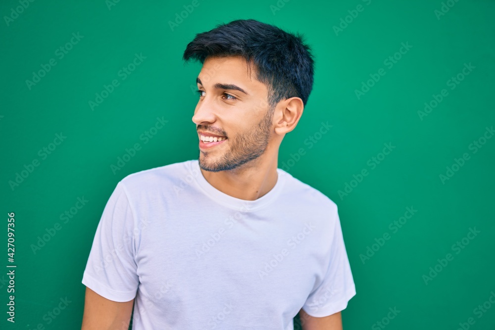 Young latin man smiling happy leaning on the wall at the city. Young latin man smiling happy leaning on the wall at the city.