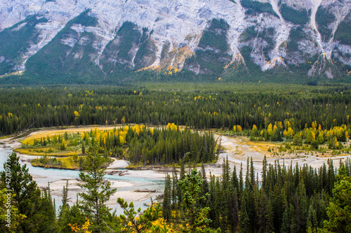 Bow River valley with turquoise glacial river surrounded by beautiful Canadian Rockies with colourful autumn trees and clouds hugging moutnains