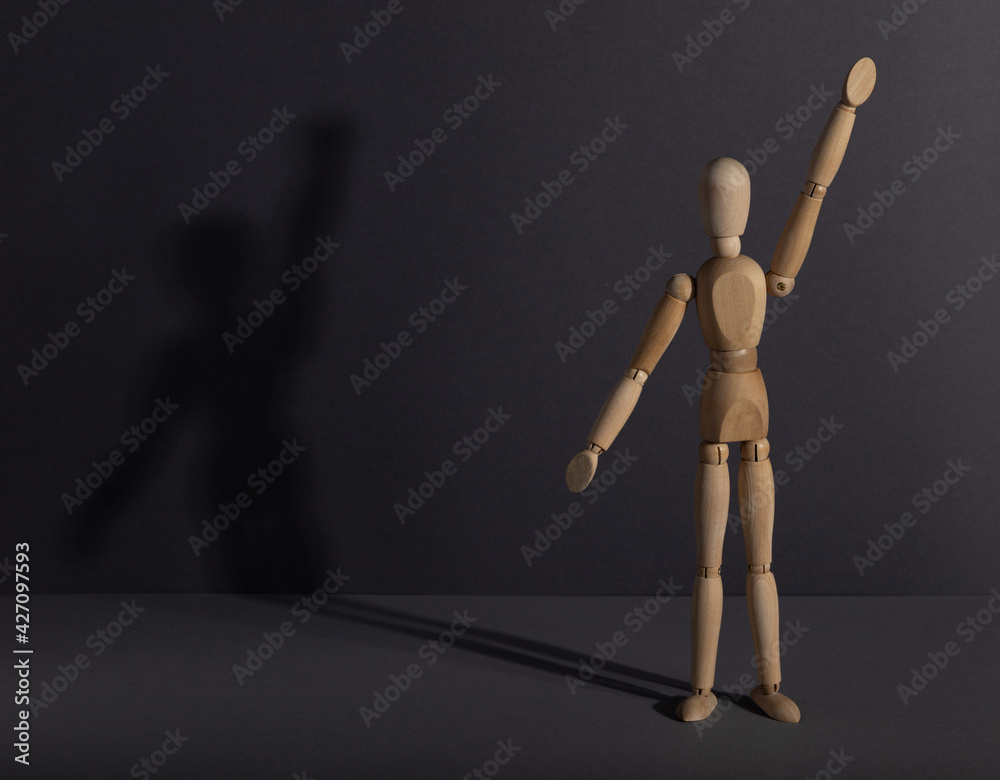 Wooden mannequin stands with raised hand on gray background. protest, attention concept. . copy space. Wooden mannequin stands with raised hand on gray background. protest, attention concept. . copy space.