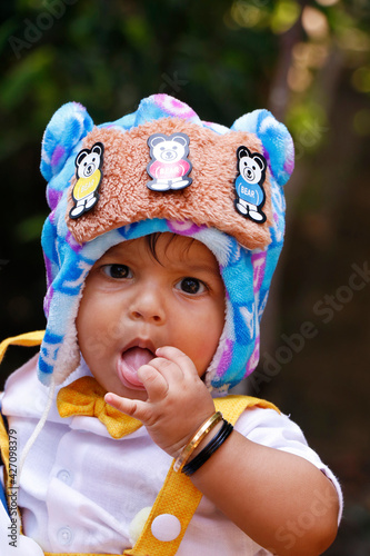 eight months old indian baby boy wearing fancy cloth cap in close up photo