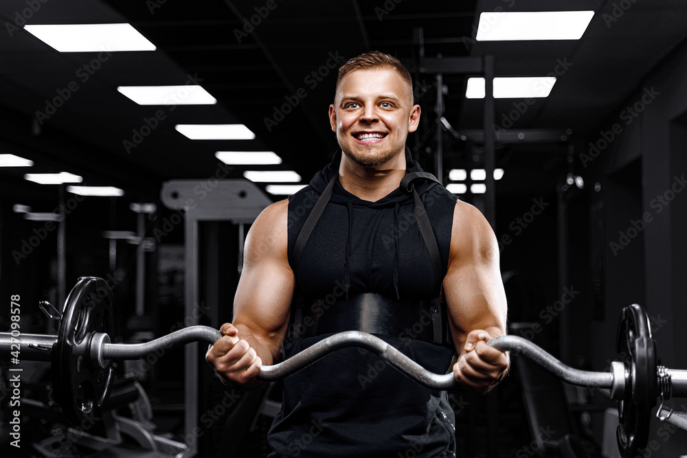 Handsome man with big muscles, posing at the camera in the gym Handsome man with big muscles, posing at the camera in the gym