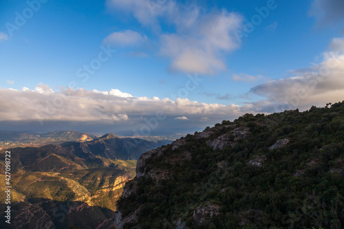 Aerial view of the Montserrat mountains on a beautiful spring day, Catalonia, Spain. Dramatic sky over the mountains. Sunlight falls through the clouds on the ground and mountains.