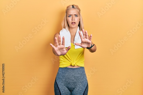 Beautiful blonde sports woman wearing workout outfit doing stop gesture with hands palms, angry and frustration expression
