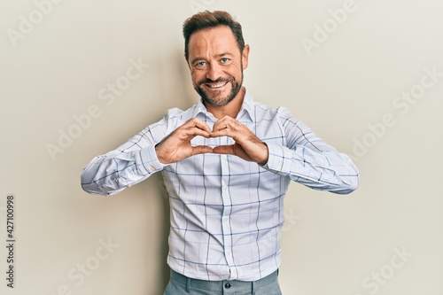 Middle age man wearing business clothes smiling in love showing heart symbol and shape with hands. romantic concept.