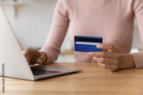 Ecommerce and online banking. Close up of young female internet store customer e-bank client make payment from home computer hold prepaid credit card in hand. Woman shopper pay for goods at web store