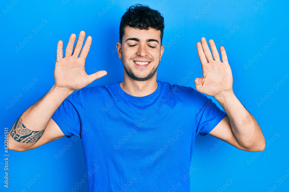 Young hispanic man wearing casual blue t shirt showing and pointing up with fingers number nine while smiling confident and happy. Young hispanic man wearing casual blue t shirt showing and pointing up with fingers number nine while smiling confident and happy.