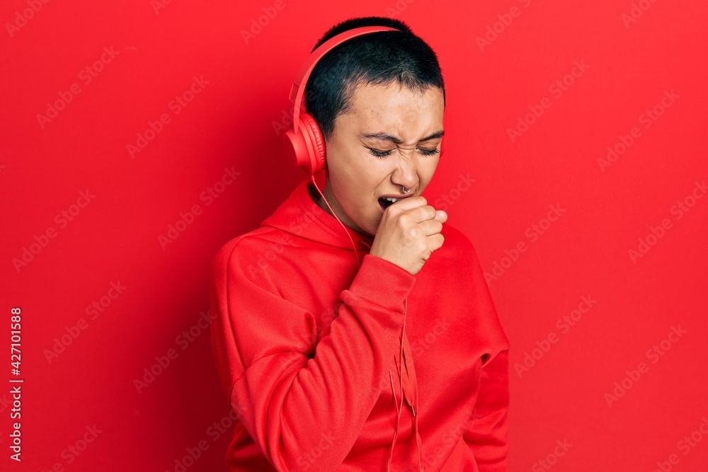 Beautiful hispanic woman with short hair listening to music using headphones feeling unwell and coughing as symptom for cold or bronchitis. health care concept.