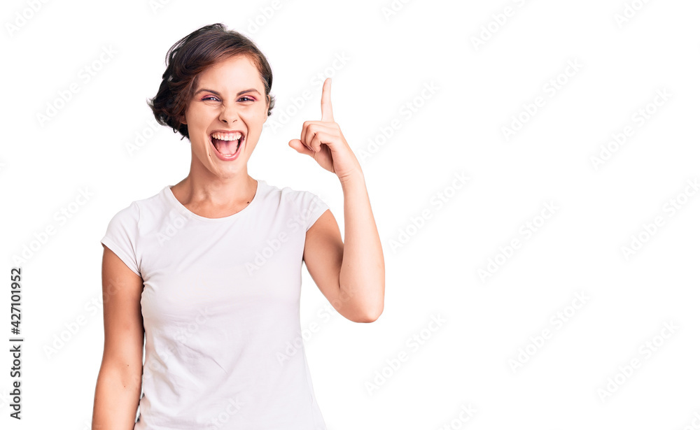 Beautiful young woman with short hair wearing casual clothes pointing finger up with successful idea. exited and happy. number one. Beautiful young woman with short hair wearing casual clothes pointing finger up with successful idea. exited and happy. number one.