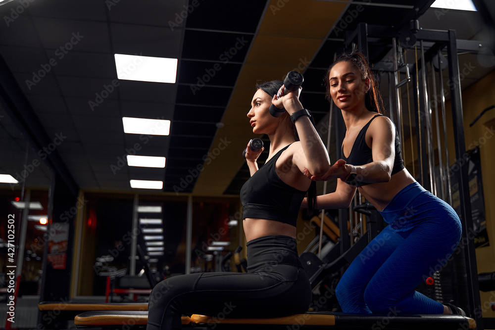Beautiful athlete woman exercising with dumbells in fitness club.