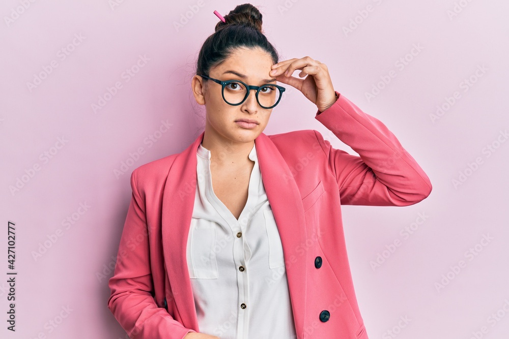 Beautiful middle eastern woman wearing business jacket and glasses worried and stressed about a problem with hand on forehead, nervous and anxious for crisis Beautiful middle eastern woman wearing business jacket and glasses worried and stressed about a problem with hand on forehead, nervous and anxious for crisis