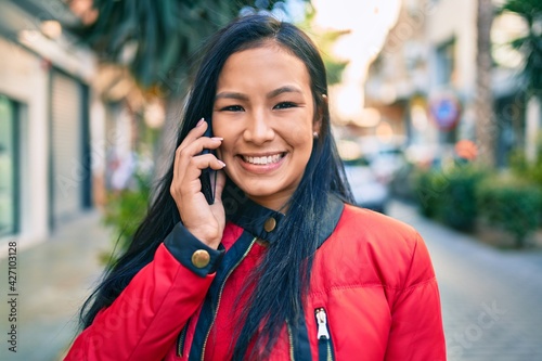 Young latin woman smiling happy talking on the smartphone at the city.