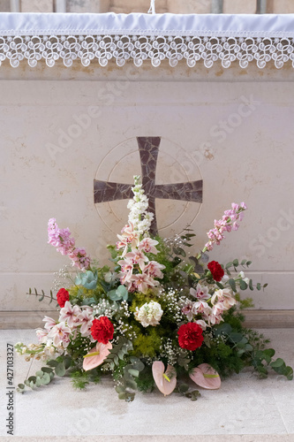 bouquet di fiori davanti una croce cristiana di un altare medievale