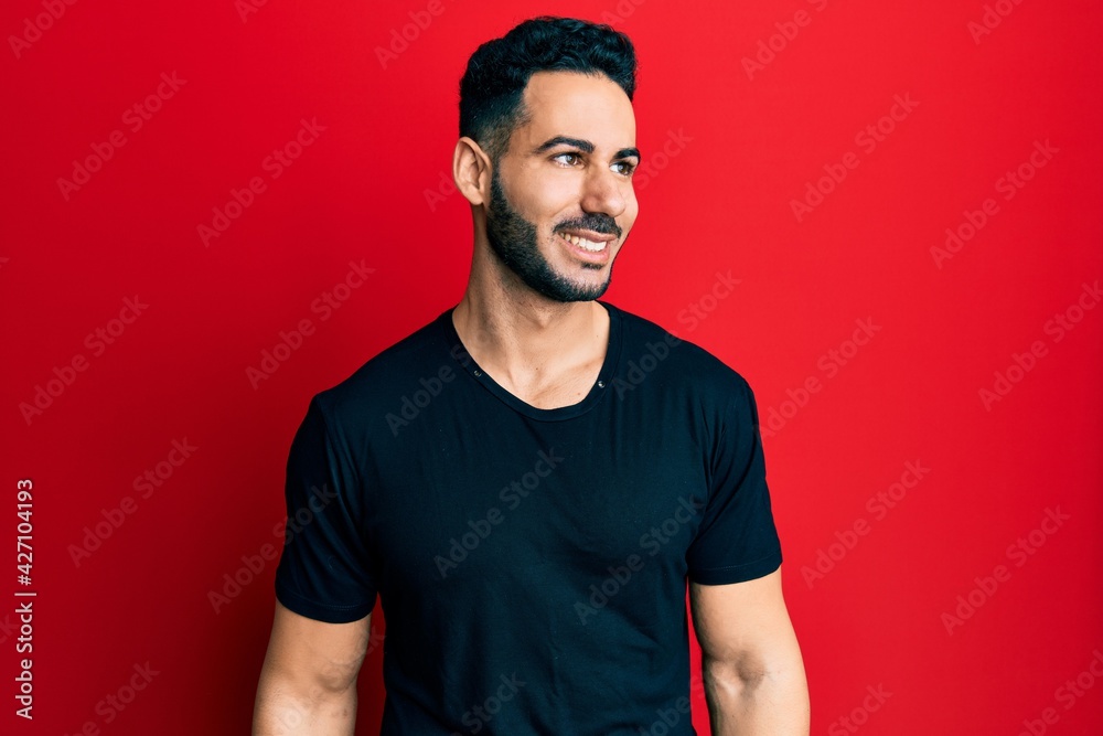 Young hispanic man wearing casual black t shirt looking to side, relax profile pose with natural face and confident smile. Young hispanic man wearing casual black t shirt looking to side, relax profile pose with natural face and confident smile.