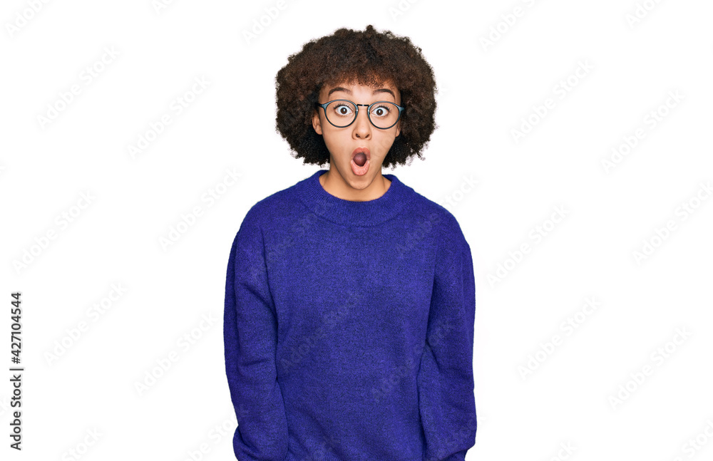 Young hispanic girl wearing casual winter sweater and glasses afraid and shocked with surprise expression, fear and excited face. Young hispanic girl wearing casual winter sweater and glasses afraid and shocked with surprise expression, fear and excited face.