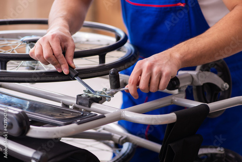 Young male repairer repairing wheel-chair indoors