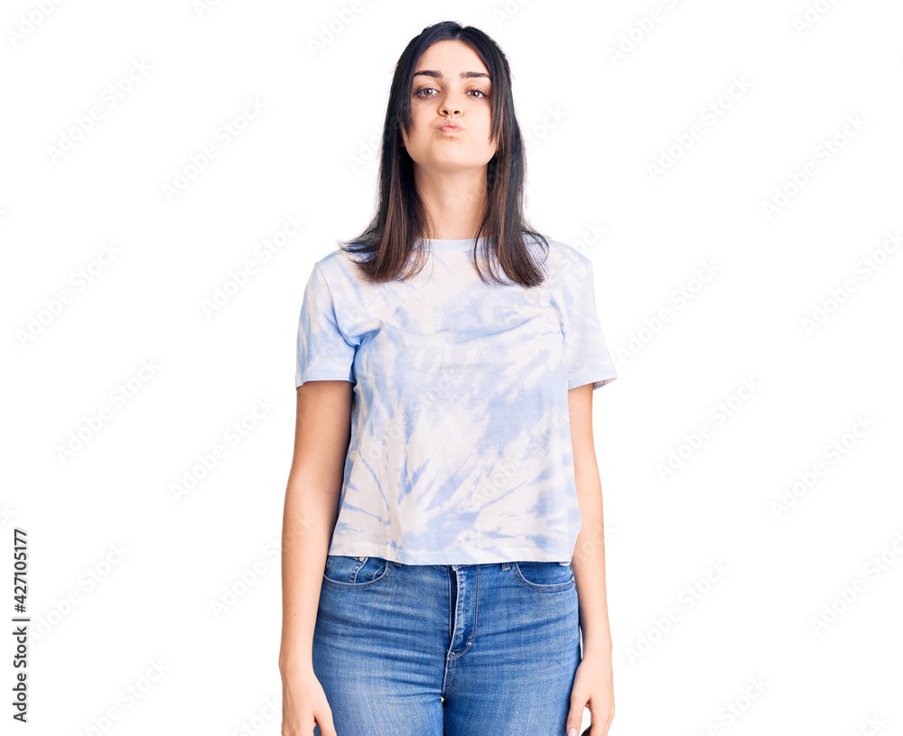Young beautiful girl wearing casual t shirt puffing cheeks with funny face. mouth inflated with air, crazy expression. Young beautiful girl wearing casual t shirt puffing cheeks with funny face. mouth inflated with air, crazy expression.