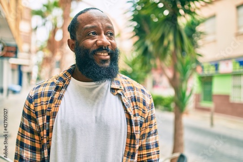 Handsome modern african american man with beard smiling positive standing at the street