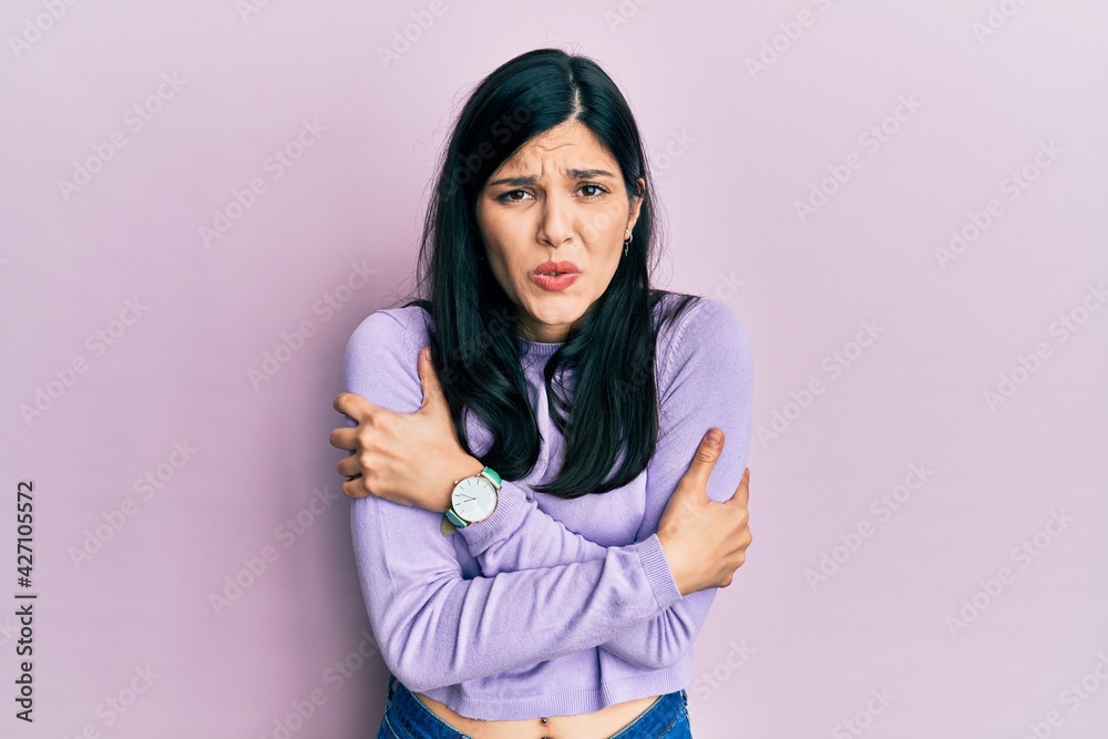 Fototapeta premium Young hispanic woman wearing casual clothes shaking and freezing for winter cold with sad and shock expression on face