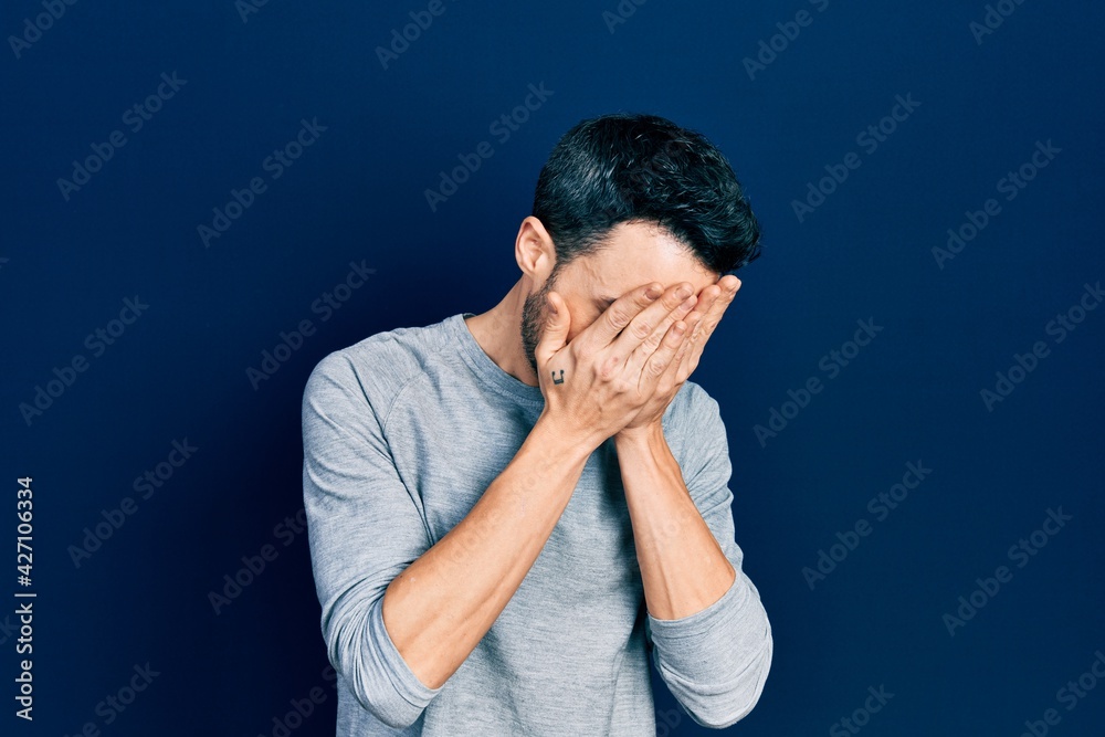 Young hispanic man wearing casual clothes with sad expression covering face with hands while crying. depression concept. Young hispanic man wearing casual clothes with sad expression covering face with hands while crying. depression concept.