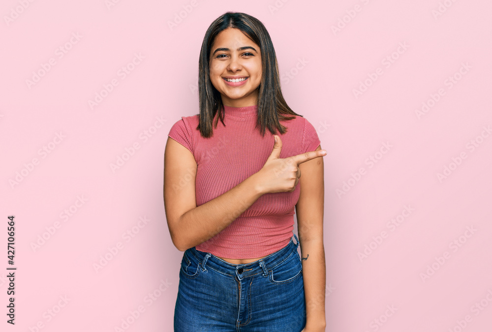 Young hispanic girl wearing casual t shirt cheerful with a smile of face pointing with hand and finger up to the side with happy and natural expression on face Young hispanic girl wearing casual t shirt cheerful with a smile of face pointing with hand and finger up to the side with happy and natural expression on face