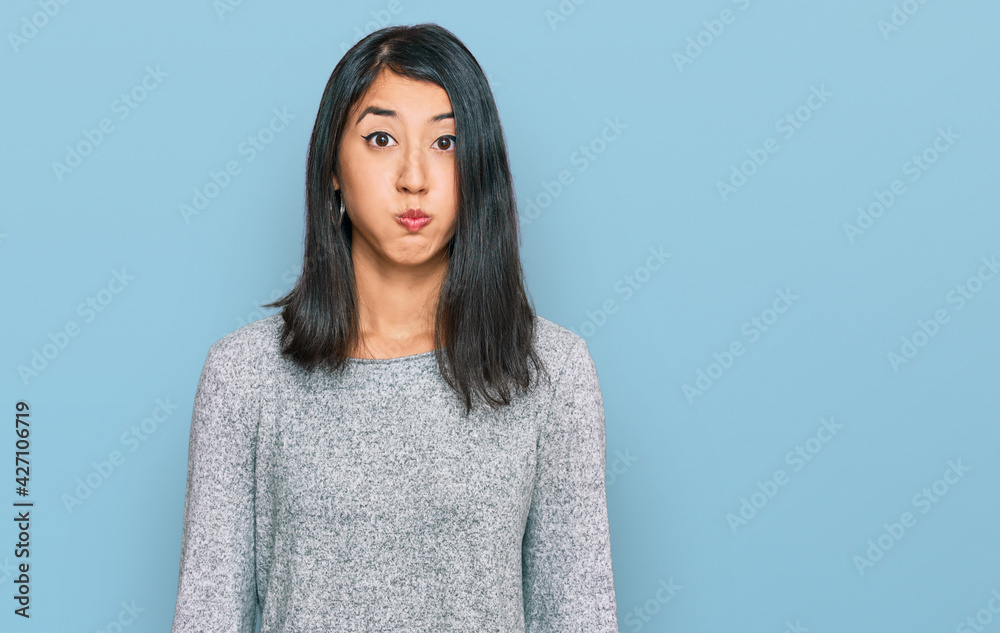 Beautiful asian young woman wearing casual clothes puffing cheeks with funny face. mouth inflated with air, crazy expression.