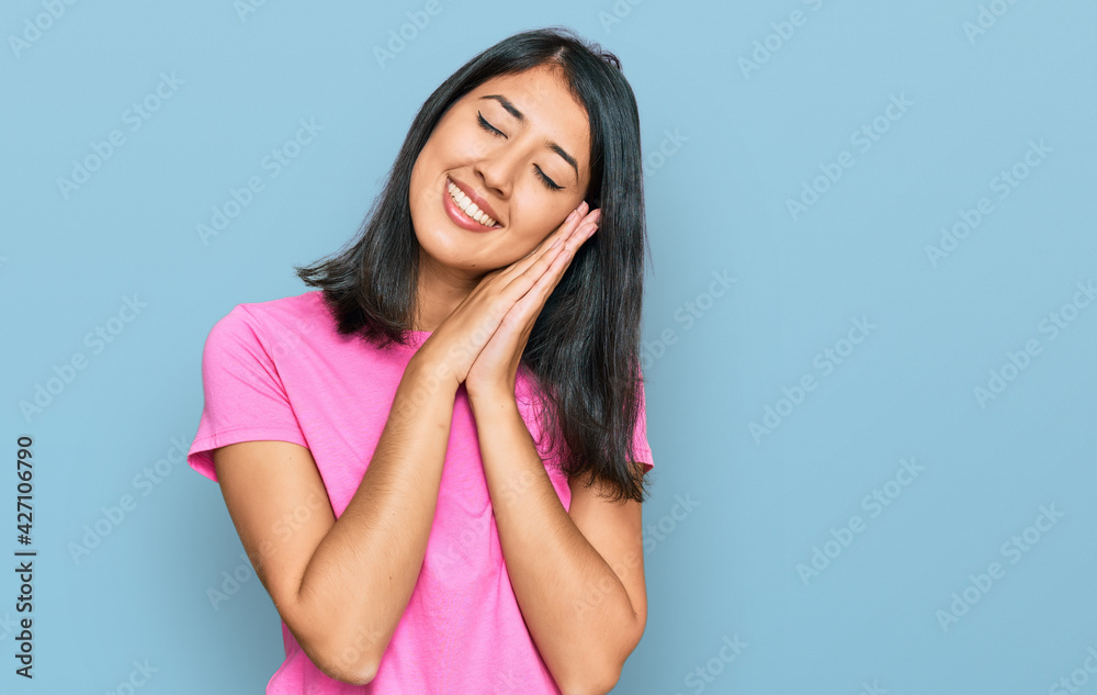 Beautiful asian young woman wearing casual pink t shirt sleeping tired dreaming and posing with hands together while smiling with closed eyes.