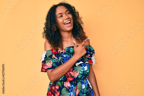 Young african american woman wearing casual clothes cheerful with a smile of face pointing with hand and finger up to the side with happy and natural expression on face