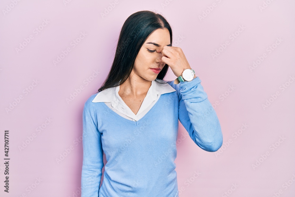 Beautiful woman with blue eyes standing over pink background tired rubbing nose and eyes feeling fatigue and headache. stress and frustration concept. Beautiful woman with blue eyes standing over pink background tired rubbing nose and eyes feeling fatigue and headache. stress and frustration concept.