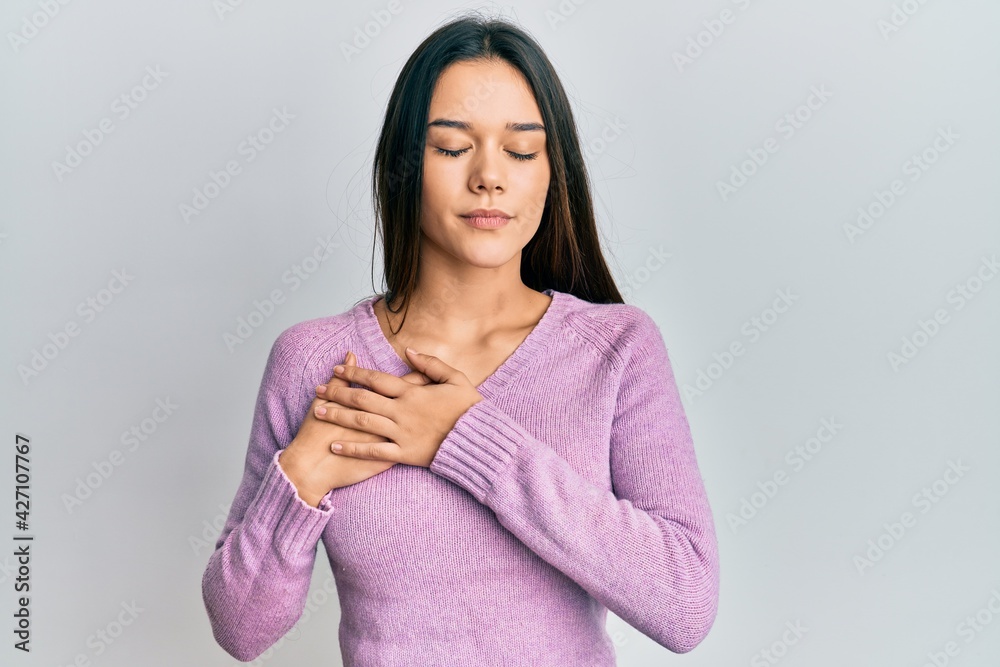 Young hispanic girl wearing casual clothes smiling with hands on chest, eyes closed with grateful gesture on face. health concept.