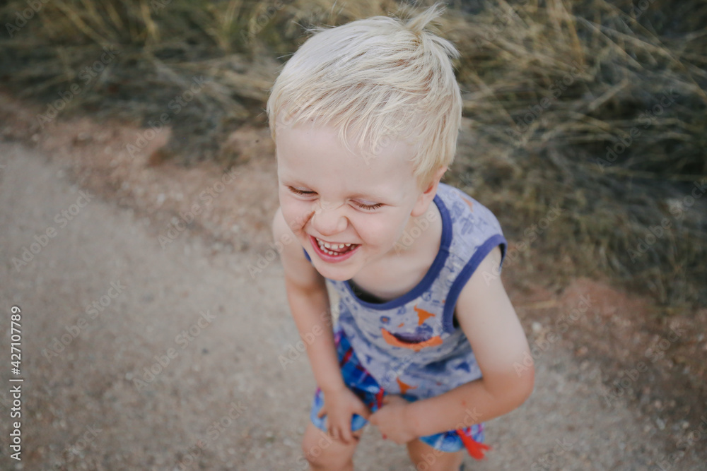 Happy little boy walking along dirt road. Huge big smile with crinkled nose and cute baby teeth, pure joy and happiness. Happy little boy walking along dirt road. Huge big smile with crinkled nose and cute baby teeth, pure joy and happiness.