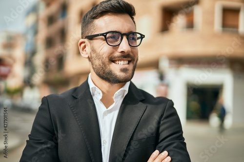 Young hispanic businessman with arms crossed smiling happy at the city.