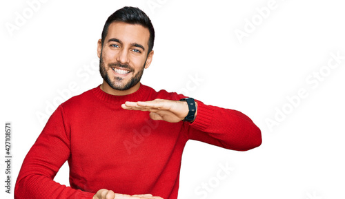 Young hispanic man wearing casual clothes gesturing with hands showing big and large size sign, measure symbol. smiling looking at the camera. measuring concept.
