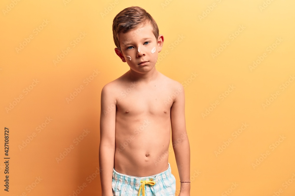 Cute blond kid wearing swimwear thinking attitude and sober expression looking self confident