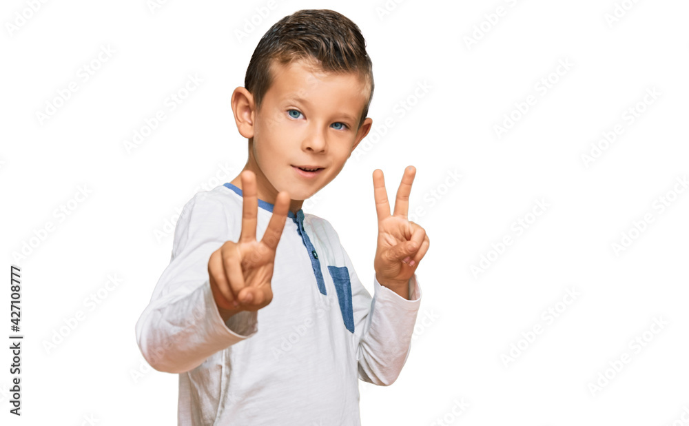 Adorable caucasian kid wearing casual clothes smiling looking to the camera showing fingers doing victory sign. number two. Adorable caucasian kid wearing casual clothes smiling looking to the camera showing fingers doing victory sign. number two.