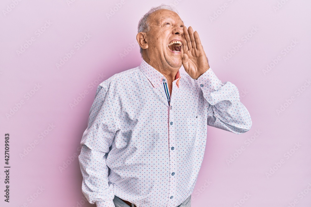 Senior caucasian man wearing casual clothes shouting and screaming loud to side with hand on mouth. communication concept. Senior caucasian man wearing casual clothes shouting and screaming loud to side with hand on mouth. communication concept.
