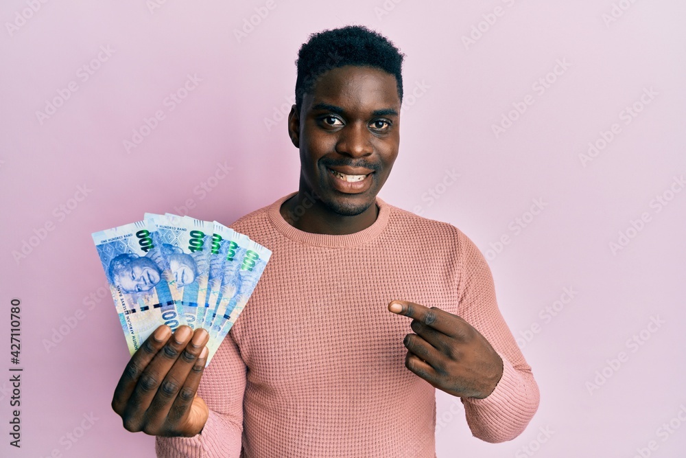 Handsome black man holding south african 100 rand banknotes smiling