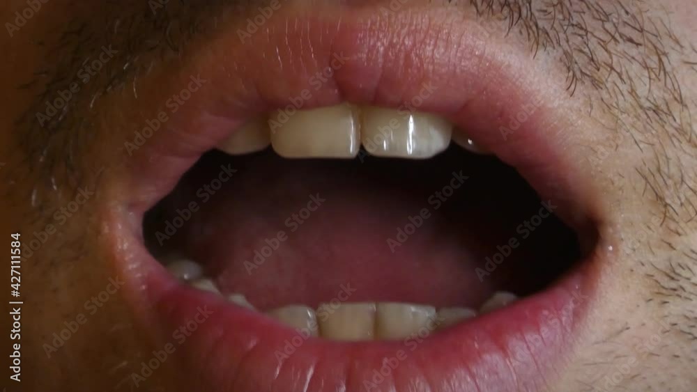 Detail of a young man's mouth, saying hi, talking, whispering, 4K detail