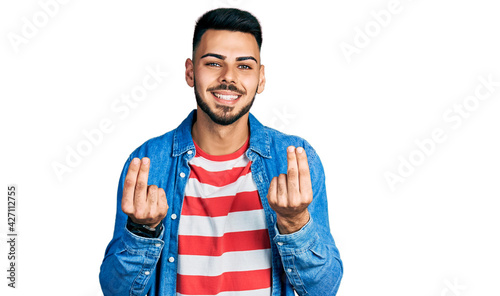 Fotografie Young hispanic man with beard wearing casual denim jacket doing money gesture wi