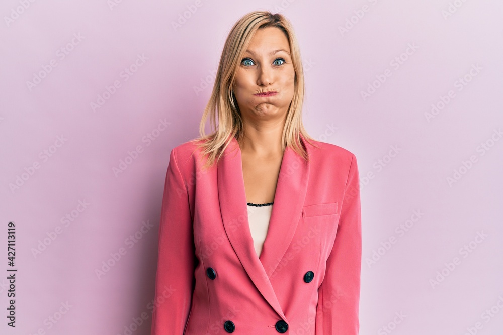 Middle age caucasian woman wearing business jacket puffing cheeks with funny face. mouth inflated with air, crazy expression. Middle age caucasian woman wearing business jacket puffing cheeks with funny face. mouth inflated with air, crazy expression.