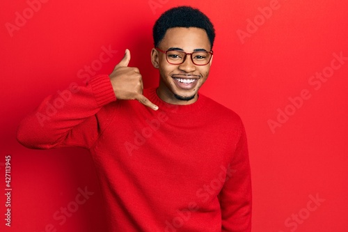 Young african american man wearing casual clothes and glasses smiling doing phone gesture with hand and fingers like talking on the telephone. communicating concepts.