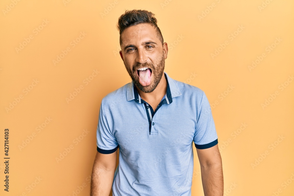 Handsome man with beard wearing casual clothes sticking tongue out happy with funny expression. emotion concept. Handsome man with beard wearing casual clothes sticking tongue out happy with funny expression. emotion concept.