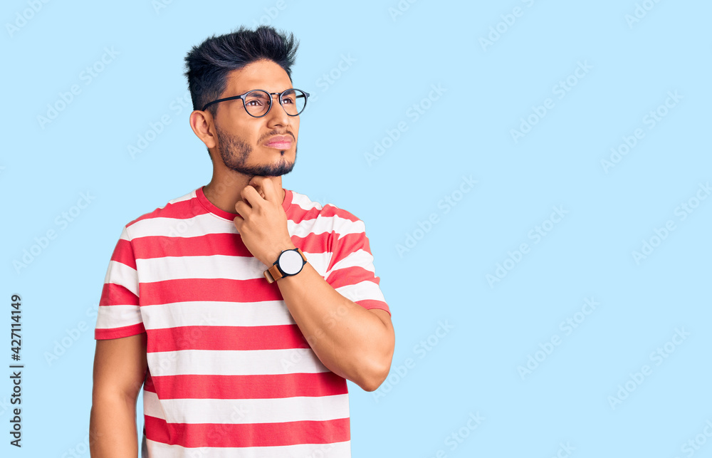 Handsome latin american young man wearing casual clothes and glasses touching painful neck, sore throat for flu, clod and infection Handsome latin american young man wearing casual clothes and glasses touching painful neck, sore throat for flu, clod and infection