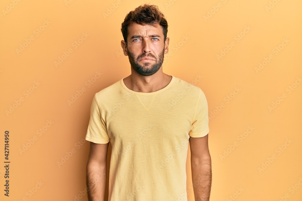 Handsome man with beard wearing casual yellow tshirt over yellow background depressed and worry for distress, crying angry and afraid. sad expression. Handsome man with beard wearing casual yellow tshirt over yellow background depressed and worry for distress, crying angry and afraid. sad expression.